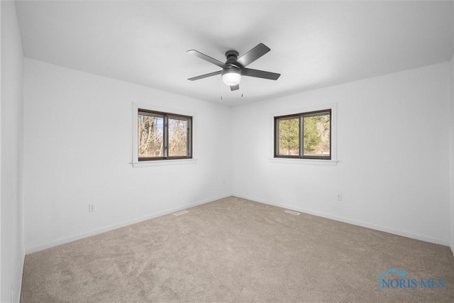 empty room featuring a wealth of natural light, ceiling fan, and carpet