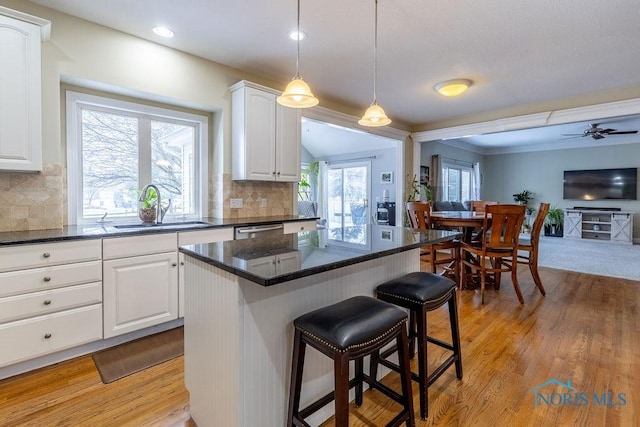 kitchen with tasteful backsplash, a center island, sink, and white cabinets