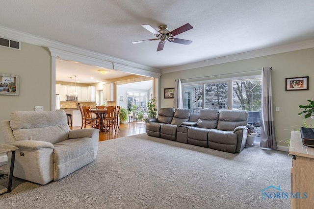 living room with crown molding, ceiling fan, carpet flooring, and a textured ceiling