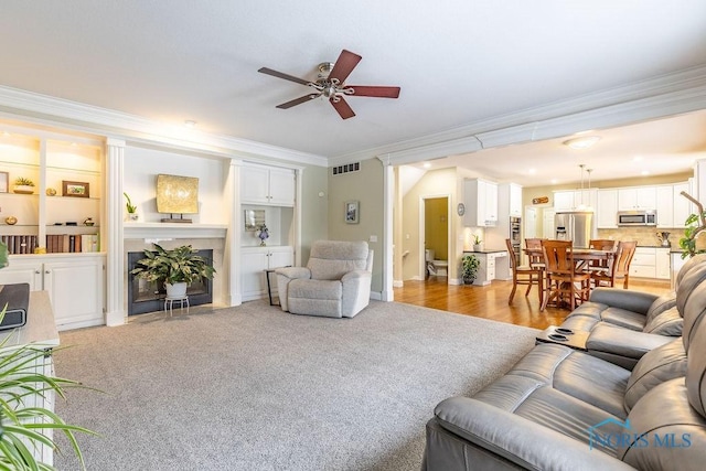 living room with light carpet, crown molding, and ceiling fan