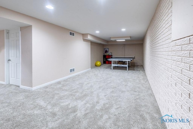 rec room featuring light colored carpet and brick wall