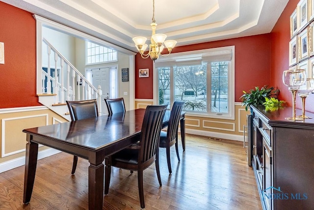 dining room featuring a tray ceiling, hardwood / wood-style floors, and a notable chandelier