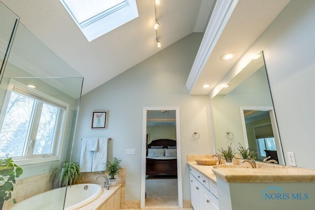 bathroom with tile patterned floors, vanity, lofted ceiling with skylight, and tiled tub