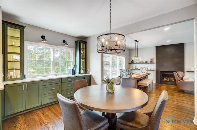 dining space featuring a notable chandelier, a fireplace, and light wood-type flooring