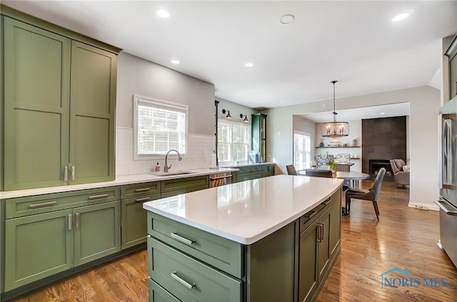 kitchen with pendant lighting, green cabinetry, sink, and backsplash