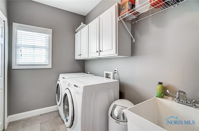 clothes washing area featuring cabinets, sink, light tile patterned floors, and washer and clothes dryer