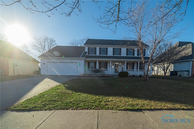 colonial-style house with a porch, a garage, and a front yard