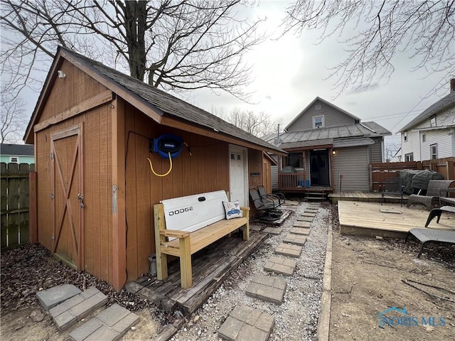 rear view of property with a wooden deck and a storage unit