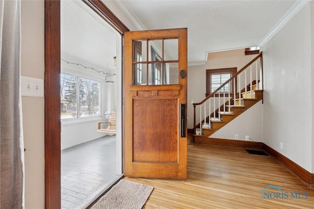 entrance foyer with ornamental molding and light hardwood / wood-style floors