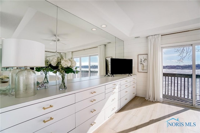 interior space with a raised ceiling, access to outside, and light hardwood / wood-style flooring