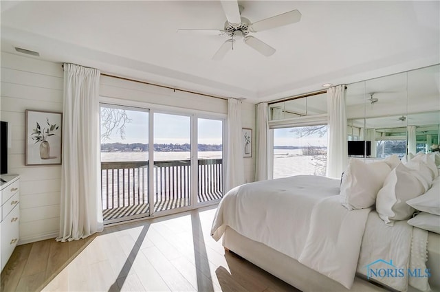 bedroom featuring light wood-type flooring, access to exterior, ceiling fan, and wood walls