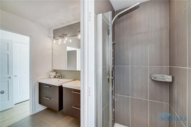 bathroom featuring vanity, tile patterned flooring, tasteful backsplash, and a shower