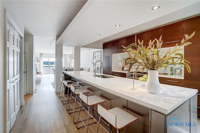 kitchen with sink, light hardwood / wood-style floors, a spacious island, and a kitchen bar