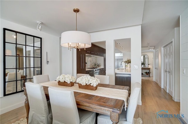 dining area featuring sink, a chandelier, and light hardwood / wood-style floors