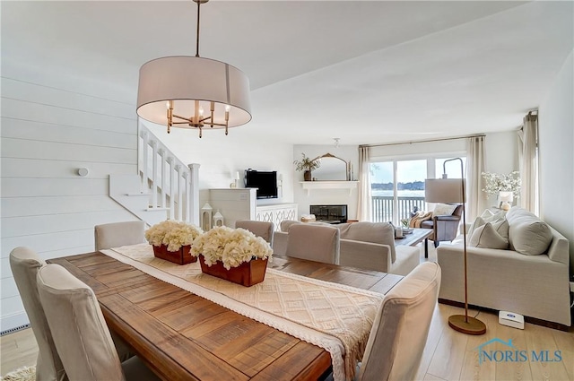 dining area featuring an inviting chandelier, wood walls, and light wood-type flooring