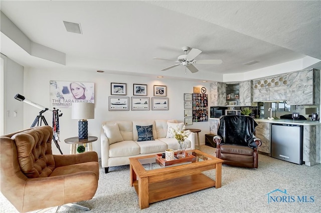 carpeted living room with ceiling fan and a textured ceiling