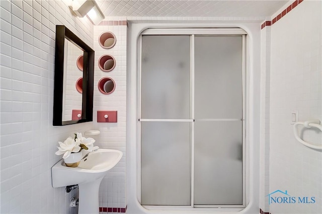 bathroom featuring a shower with shower door and tile walls