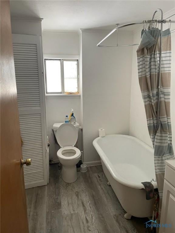 bathroom with toilet, crown molding, vanity, a bath, and hardwood / wood-style flooring