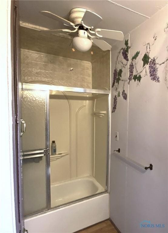 bathroom with ceiling fan, enclosed tub / shower combo, and wood-type flooring