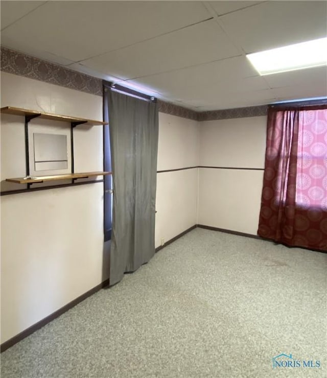 carpeted spare room featuring a drop ceiling