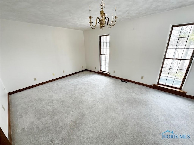 empty room featuring a notable chandelier and carpet flooring