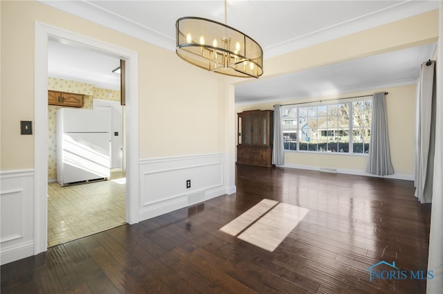 empty room featuring dark wood-type flooring, crown molding, and a chandelier