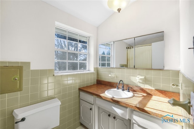 bathroom with vanity, vaulted ceiling, tile walls, and toilet