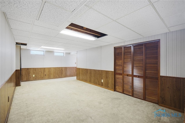 basement with light colored carpet and a drop ceiling