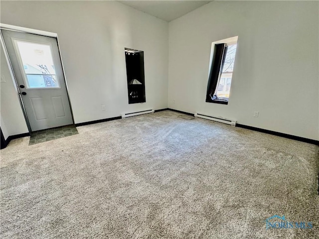 spare room featuring light carpet and a baseboard heating unit