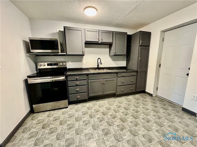 kitchen featuring stainless steel appliances, sink, gray cabinetry, and a textured ceiling