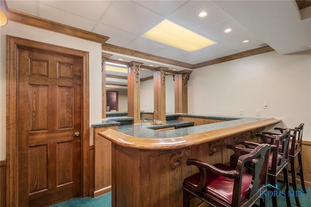 bar with crown molding, wooden walls, a drop ceiling, and dark carpet