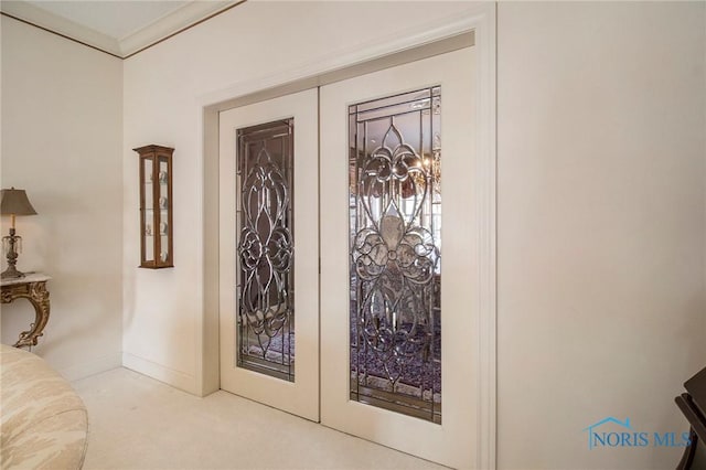 doorway featuring light carpet, ornamental molding, and french doors