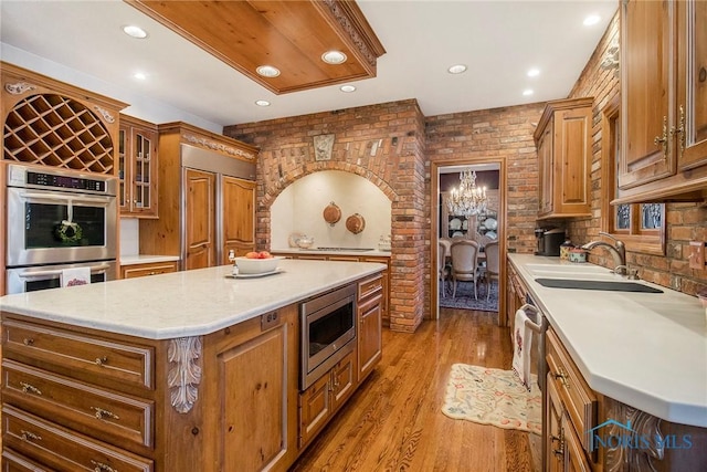 kitchen with brick wall, appliances with stainless steel finishes, a center island, and sink