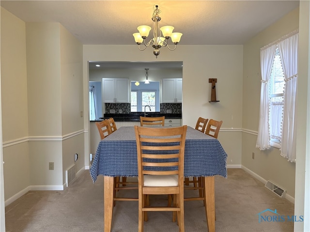 carpeted dining area with an inviting chandelier