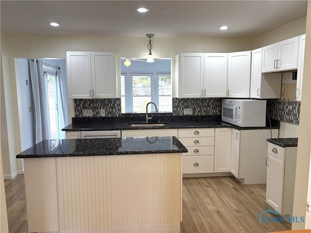 kitchen with pendant lighting, sink, light hardwood / wood-style flooring, white cabinets, and a kitchen island