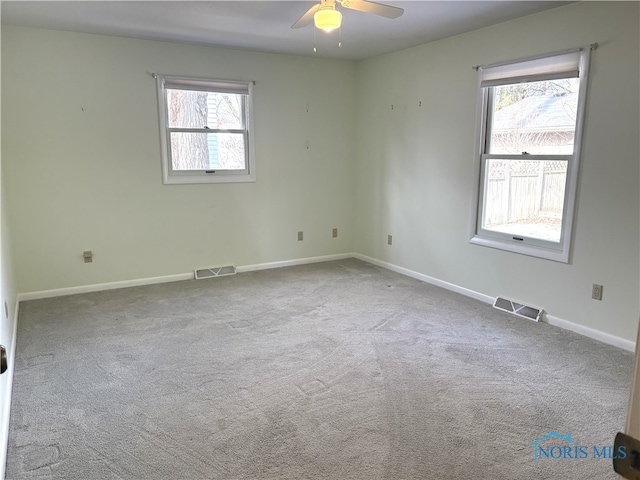 empty room featuring light carpet, a wealth of natural light, and ceiling fan