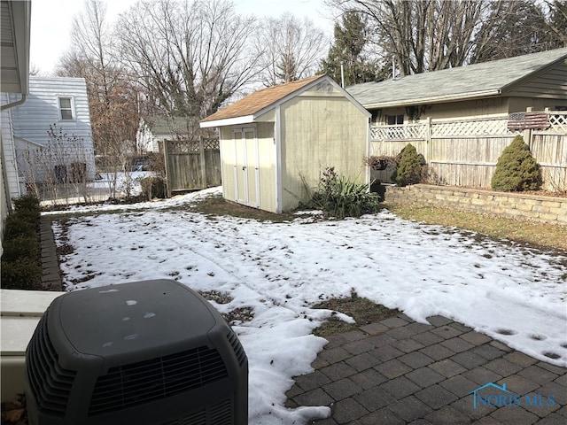 snowy yard featuring a shed