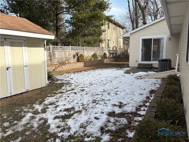 snowy yard with a storage shed and central AC unit