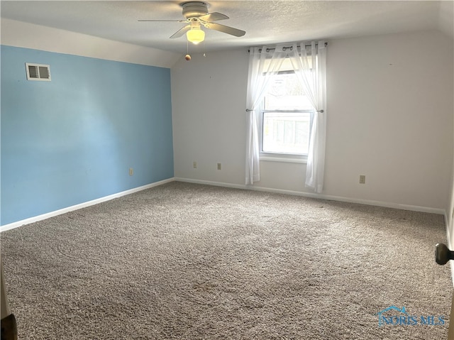 carpeted spare room featuring ceiling fan, vaulted ceiling, and a textured ceiling