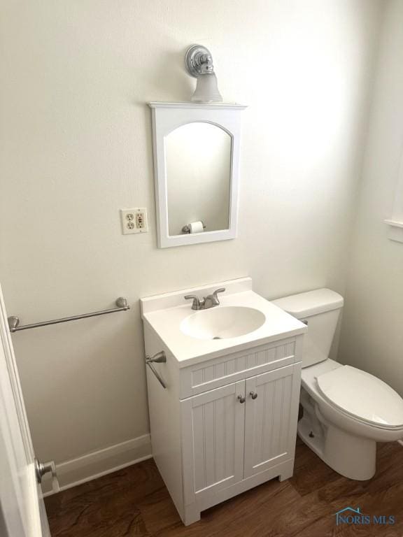 bathroom with wood-type flooring, vanity, and toilet