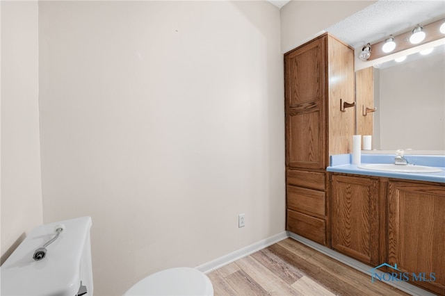 bathroom with hardwood / wood-style flooring, vanity, and toilet