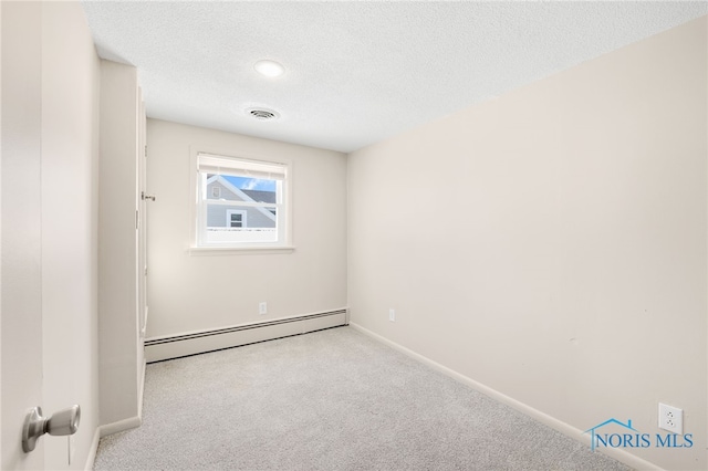 spare room featuring a baseboard radiator, light colored carpet, and a textured ceiling