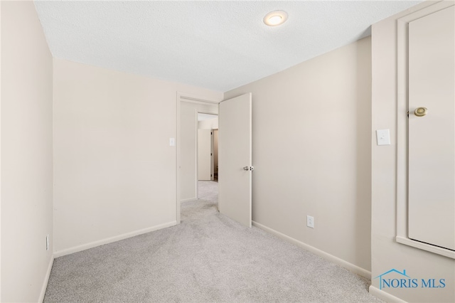 spare room featuring light colored carpet and a textured ceiling