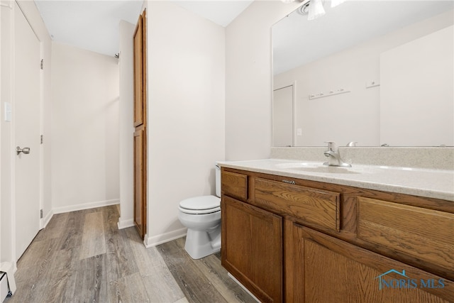 bathroom featuring vanity, toilet, hardwood / wood-style floors, and a baseboard heating unit