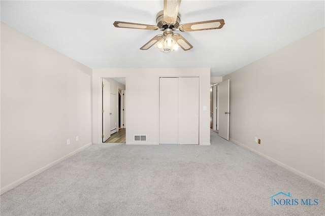 unfurnished bedroom with ceiling fan, a closet, and light carpet