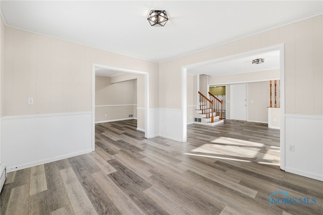 spare room with baseboard heating, wood-type flooring, and crown molding