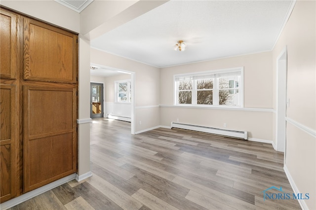 unfurnished dining area with baseboard heating, a healthy amount of sunlight, and light wood-type flooring