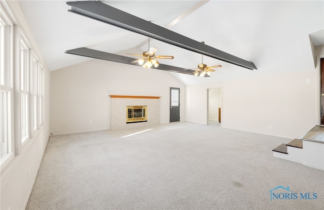 unfurnished living room featuring beamed ceiling, light carpet, a tile fireplace, and a wealth of natural light