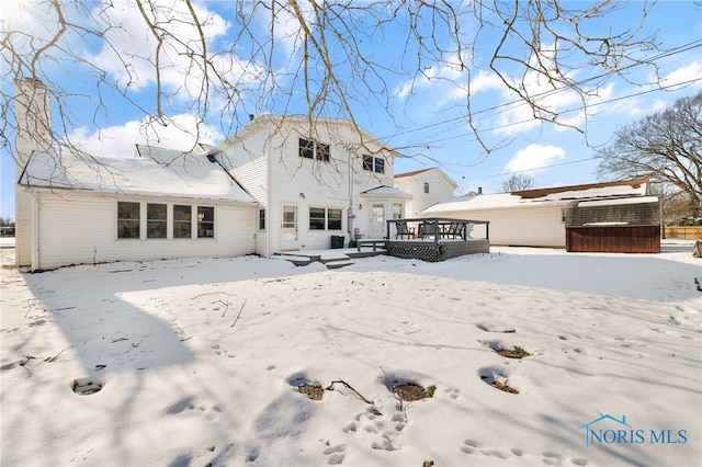 snow covered back of property featuring a wooden deck