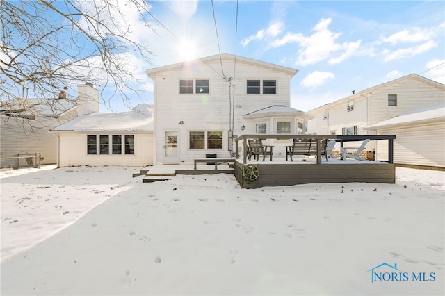 snow covered back of property featuring a deck